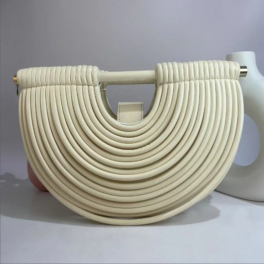 Beige woven handbag with a gold handle on a light gray background