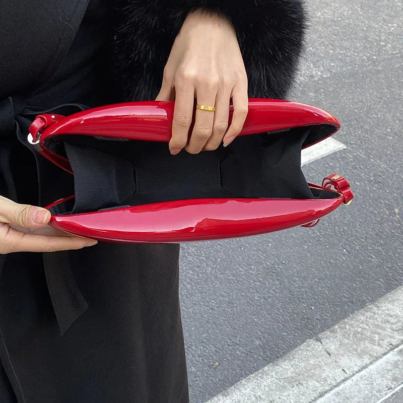 Person holding a red handbag with a black coat and fur collar.
