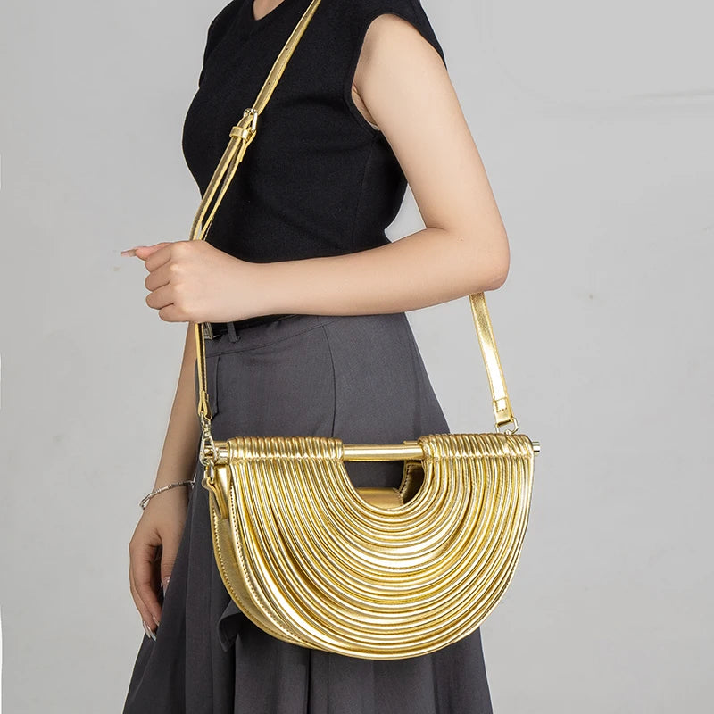 Gold handbag held by a person against a gray background