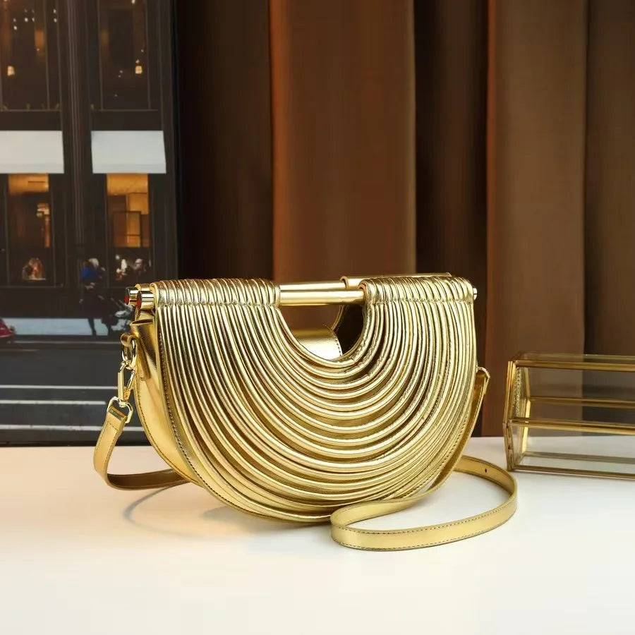 Gold handbag with a textured design on a reflective surface with a blurred background