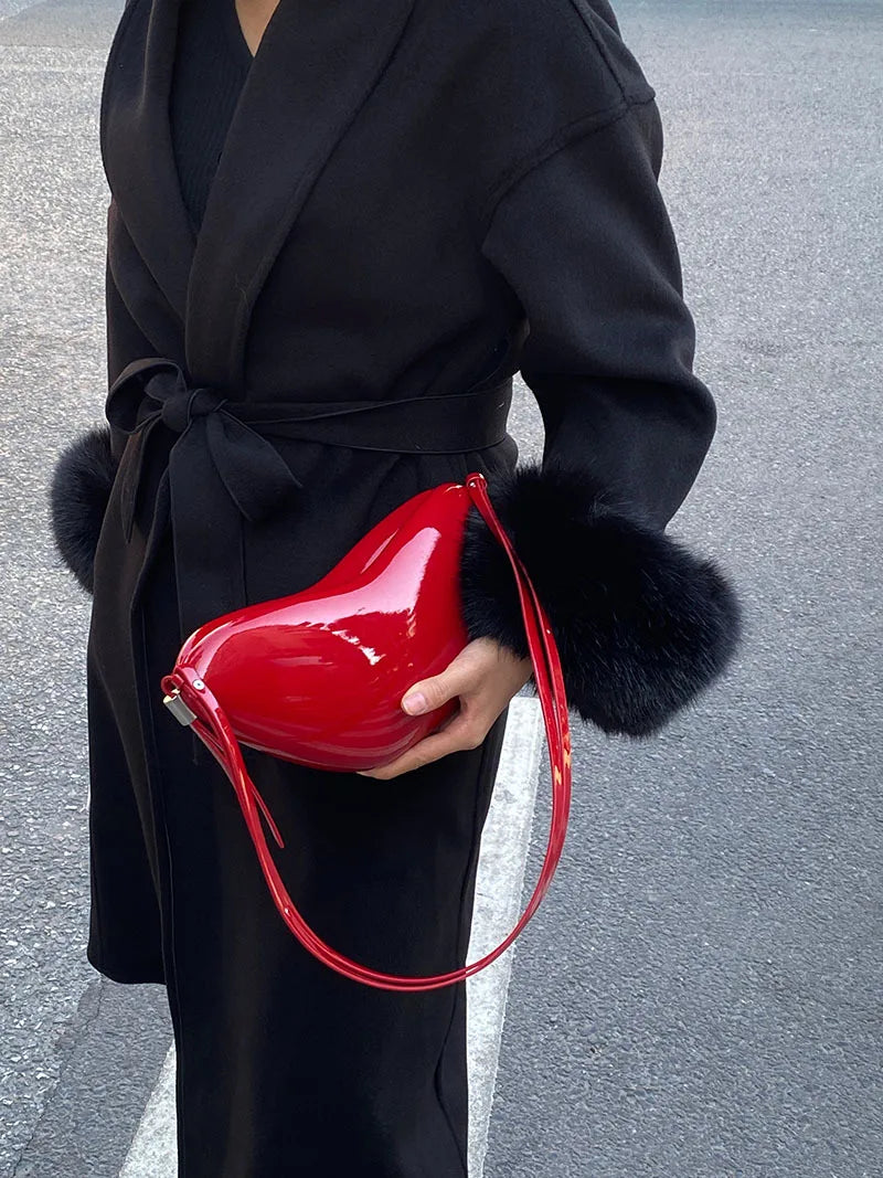 Person holding a red handbag with a black coat and fur-trimmed cuffs.