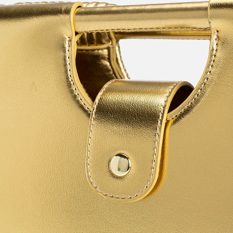 Close-up of a gold handbag handle with a metallic finish.