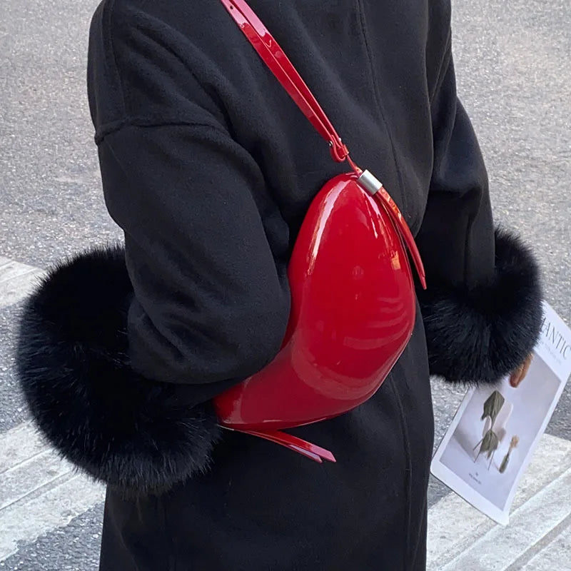 Person holding a red heart-shaped bag with black fur accents on a street.
