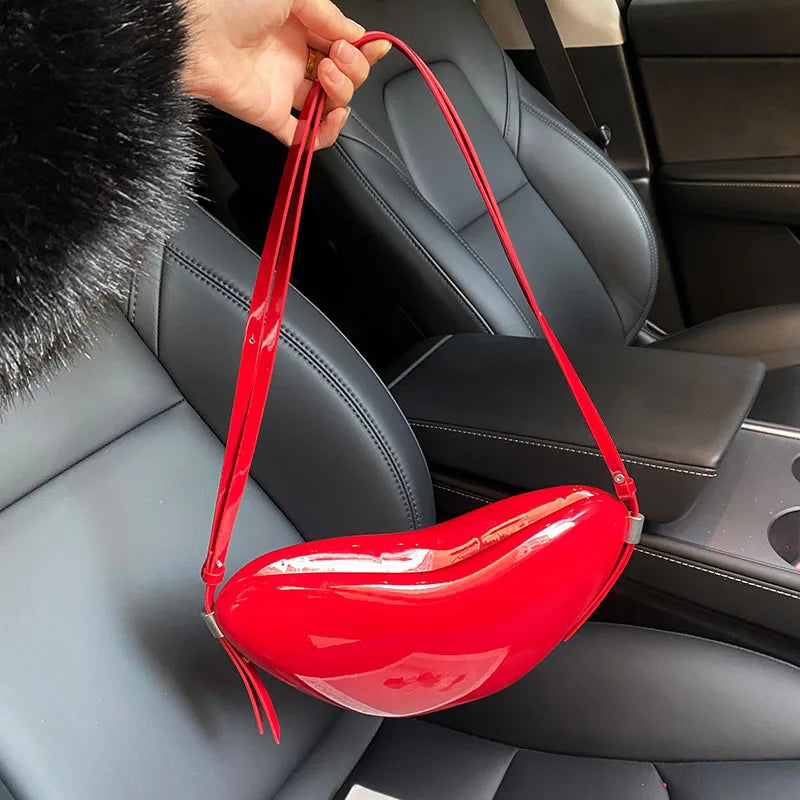 Red lip-shaped bag held by a person inside a car.